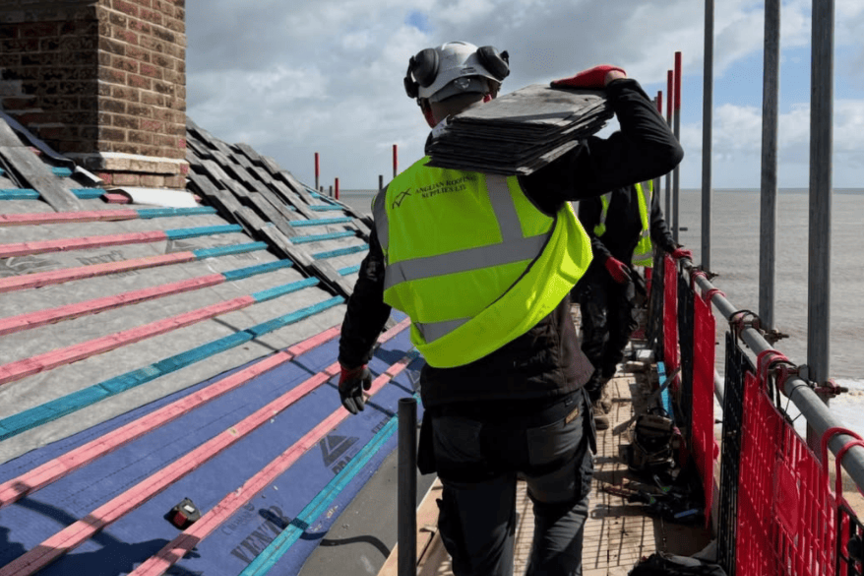 Roofer carrying roof tiles during a content shoot for a Norfolk construction business
